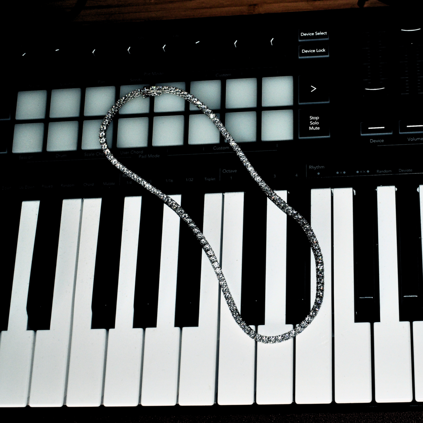 Iced out Moissanite tennis chain necklace laid on a musical keyboard, showcasing luxury and brilliance.