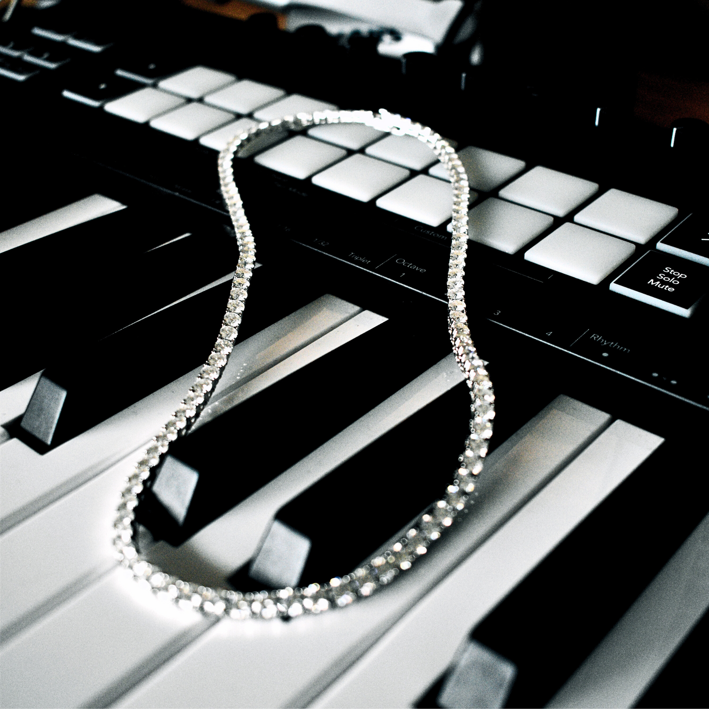 Iced out Moissanite tennis chain necklace laid on a keyboard, showcasing VVS clarity and luxurious design.