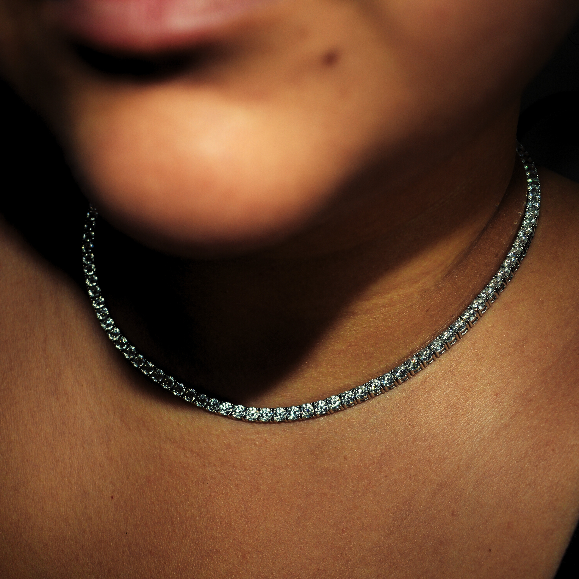 Iced out moissanite tennis chain necklace on neckline, showcasing VVS clarity diamonds for luxury style.